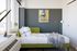 Chic bedroom featuring a modern green daybed, vibrant wall art, and a large window providing abundant natural light.