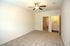 Bright, spacious bedroom featuring plush carpet, a ceiling fan, and modern lighting, offering a cozy and inviting atmosphere.