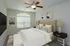 Elegant bedroom with a plush, tufted bed, modern decor, ceiling fan, and natural light from a large window.