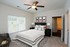 Bright and inviting bedroom with elegant decor, featuring a cozy bed, stylish artwork, and a ceiling fan for comfort.