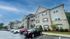 Charming brick apartment complex with elegant balconies and ample parking in a lush, green setting.