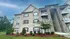 Charming apartment exterior with beautiful brickwork, elegant balconies, and lush landscaping against a clear blue sky.