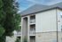 Elegant apartment building with modern design, featuring private balconies and surrounded by lush greenery.