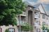 Elegant apartment building with stone facade and charming balconies surrounded by lush greenery, perfect for modern living.