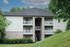 Charming apartment building with three levels of balconies, nestled in lush greenery and offering a serene living environment.