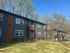 Charming brick apartment complex with modern design, surrounded by lush greenery and clear blue skies.