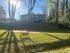 Charming apartment building nestled in a lush green setting with a sunny outdoor area featuring a cozy wooden swing.