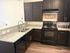 Modern kitchen with elegant dark wood cabinets, granite countertops, and stainless steel appliances, offering a warm and inviting atmosphere.