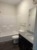 Modern bathroom featuring a sleek granite countertop, elegant dark cabinetry, and a spacious bathtub with a clean, bright aesthetic.