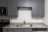 Chic kitchen with sleek gray cabinets and modern stainless-steel appliances, highlighting granite countertops and a stylish under-mount sink.