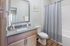 Modern bathroom adorned with elegant granite countertops, sleek cabinetry, and a calming blue shower curtain.