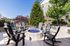 Charming outdoor patio featuring cozy Adirondack chairs encircling a stylish fire pit, set against lush greenery and sunny skies.