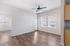 Bright and modern living space with elegant wood flooring, ceiling fan, and ample natural light from large windows.