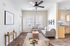 Bright and spacious living area with light wood flooring, modern gray sofa, elegant coffee table, and sleek kitchen with natural wood cabinets.