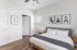 Contemporary bedroom with elegant decor, featuring a cozy bed, natural light from a large window, and minimalist artwork on the wall.