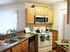 Agora at Port Richey, kitchen, light colored wood cabinets, white stove, microwave above stove, entrance to laundry closet, kitchen sink and faucet, simulated hard wood floors