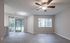 Bright, spacious living room with large windows and modern ceiling fan, offering natural light and serene views.