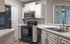 Modern kitchen with sleek black appliances, white cabinetry, and ample counter space, beautifully lit by natural light from large windows.