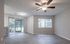 Bright and spacious living area with modern ceiling fan, featuring large windows and elegant hardwood flooring, overlooking a lush green garden.