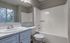 Modern bathroom with a sleek vanity, large mirror, and a pristine bathtub adjacent to a bright window.