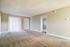 Inviting living room with plush carpet, neutral walls, and abundant natural light from large window blinds.