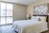 Inviting bedroom in a serene apartment with a large window, elegant decor, and a cozy bed adorned with textured bedding.