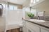 Modern bathroom with elegant granite countertop, sleek cabinetry, and a refreshing plant accent. Natural light filters through the window, illuminating the stylish bath area.