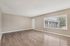 Bright and spacious empty room featuring elegant wood flooring, large window with a view, and neutral walls ideal for customization.