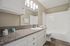 Elegant bathroom featuring a sleek granite countertop, modern lighting, and a pristine white bathtub with a stylish curved shower rod.