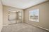 Bright and welcoming bedroom featuring neutral tones, plush carpeting, large mirrored closet, and natural light streaming through wide windows.
