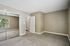 Bright and inviting bedroom with a large mirrored closet, plush carpet, and a charming view through the window.