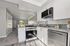 Modern kitchen with sleek granite countertops, white cabinets, and stainless steel appliances leading into a cozy living area with natural light.