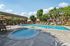 Inviting apartment complex outdoor area with a sparkling swimming pool, relaxing jacuzzi, and sunlit lounging spaces surrounded by lush greenery.