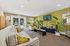 Bright and inviting living room with modern decor, cozy seating, and lush plants. Features a stylish entertainment setup and expansive windows overlooking a serene outdoor area with a fountain.