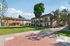 Charming apartment complex with vibrant exteriors, lush green lawns, and mature trees, offering a welcoming community atmosphere.