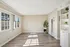Bright and airy living space with large windows, elegant laminate flooring, built-in shelving, and a touch of greenery for a modern and relaxing ambiance.