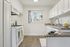 Bright and modern kitchen with sleek white cabinets, granite countertops, and a sunny window view of palm trees.