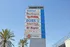 Vibrant shopping mall sign at Anaheim Plaza showcasing top stores including Walmart, Burlington, T.J.Maxx, Ross, Smart & Final, El Super, Ulta Beauty, and Crunch Fitness, framed by beautiful palm trees.