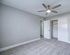 Elegant bedroom with plush carpeting, modern ceiling fan, and ample closet space, creating a serene and inviting atmosphere.