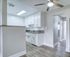 Bright and modern kitchen with sleek countertops, elegant cabinetry, and a ceiling fan, offering a welcoming and stylish space.