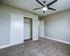 Bright and spacious bedroom with plush carpet, sleek ceiling fan, and modern closet.