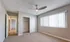 Bright and spacious bedroom with modern ceiling fan, plush carpet, and ample natural light from wide window.