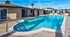 Inviting outdoor pool area with crystal clear water, surrounded by a well-maintained patio and chairs for relaxation under the blue sky.