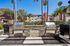 Chic outdoor space featuring modern stainless steel grills and lush landscaping, perfect for entertaining with a view of stylish apartment balconies and tropical palm trees.
