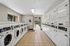Modern laundry facility featuring rows of washers and dryers with ample natural light and a view of the garden through the open door.