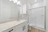 Modern bathroom featuring sleek white cabinetry, elegant granite countertop, and a spacious glass-enclosed shower.