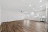 Spacious open living area with modern wood flooring, sleek kitchen cabinetry, and abundant natural light.