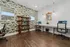 Modern home office space with stylish floral wallpaper, elegant shelving, and dual workstations with chic seating.