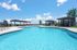 Luxurious outdoor swimming pool with stylish pergolas and sun loungers, set against a vibrant blue sky.