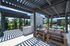 Chic outdoor patio with shaded pergola, modern stone fireplace, and stylish wooden seating, perfect for relaxation and entertainment.